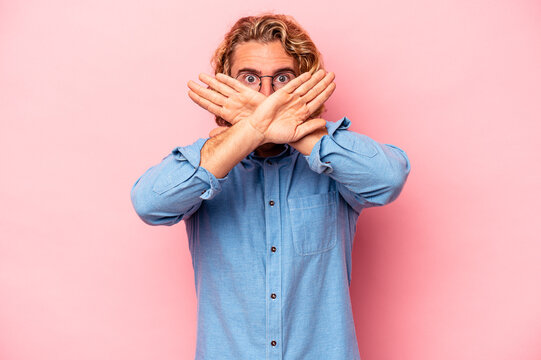 Young caucasian man isolated on pink background doing a denial gesture