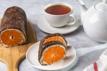 Sweet chocolate roll with tangerine filling and a cup of hot tea.