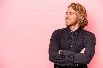 Fototapeta premium Young caucasian man isolated on pink background smiling confident with crossed arms.
