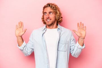 Young caucasian man isolated on pink background being shocked due to an imminent danger