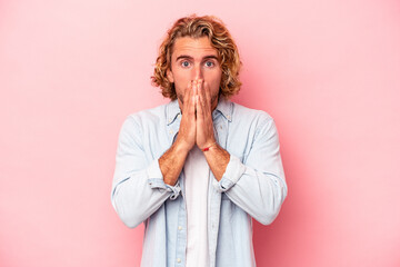 Young caucasian man isolated on pink background covering mouth with hands looking worried.