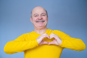 Senior man with smile showing heart symbol with his hands