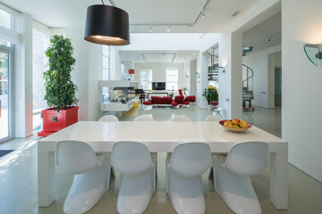 Modern interior of spacious living room. White dinner table and chairs.