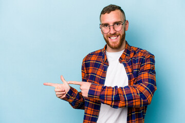 Young caucasian man isolated on blue background excited pointing with forefingers away.