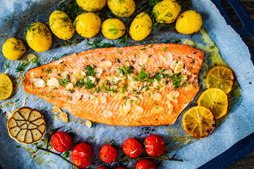 One sheet pan Roast trout fillet with potatoes and vegetable salad served on black stone plate on...