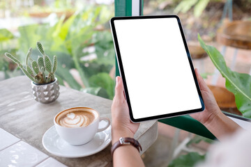 Mockup image of a woman holding digital tablet with blank desktop screen with coffee cups on the...