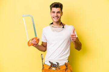 Young electrician caucasian man isolated on yellow background.smiling and raising thumb up