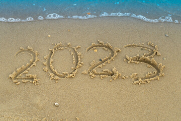 Fototapeta na wymiar The numbers 2023 are written on a sandy seashell beach. Wave and surf. Summer New Year. Vacation, resort and recreation. Nature. Sea coast.
