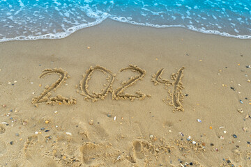 The numbers 2024 are written on a sandy seashell beach. Wave and surf. Summer New Year. Vacation, resort and recreation. Nature. Sea coast.