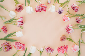 Naklejka na ściany i meble Round border frame of various tulips on a pastel beige background.