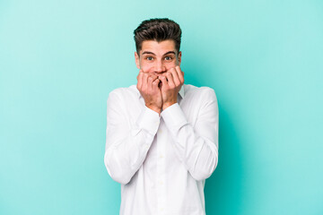 Young caucasian man isolated on blue background biting fingernails, nervous and very anxious.