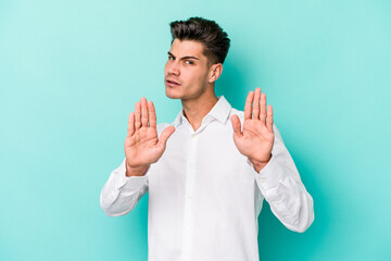 Young caucasian man isolated on blue background standing with outstretched hand showing stop sign, preventing you.