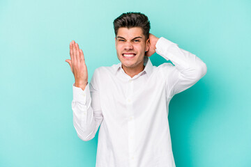 Young caucasian man isolated on blue background screaming with rage.
