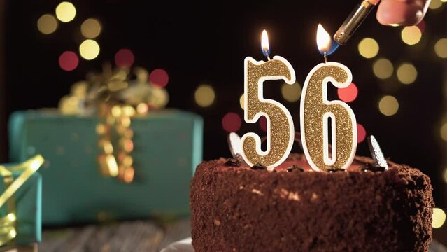 Number fifty six birthday candle on sweet cake on the table, 56th birthday. Fire from the lighter, blow out the holiday candle.