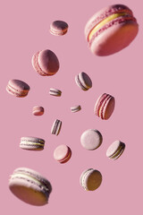 Flying macaroons cakes on a pink background. Pattern with falling macaroons