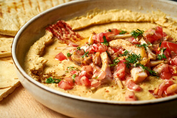 Yummy oriental hummus with olive oil, tomato and chicken in a white bowl. Close-up, selective focus