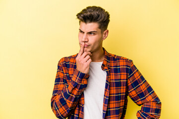 Young caucasian man isolated on yellow background keeping a secret or asking for silence.