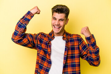 Young caucasian man isolated on yellow background cheering carefree and excited. Victory concept.