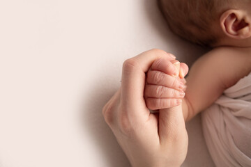 The hand of a sleeping newborn in the hand of mother and father close-up. Tiny fingers of a...