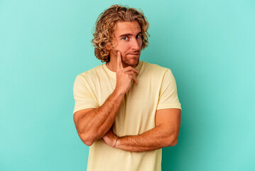 Young caucasian man isolated on blue background contemplating, planning a strategy, thinking about the way of a business.