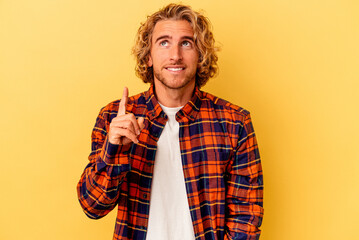 Fototapeta premium Young caucasian man isolated on yellow background indicates with both fore fingers up showing a blank space.