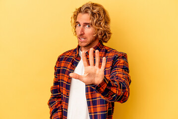 Young caucasian man isolated on yellow background being shocked due to an imminent danger
