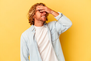 Young caucasian man isolated on yellow background laughs joyfully keeping hands on head. Happiness concept.