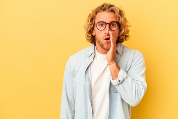Young caucasian man isolated on yellow background is saying a secret hot braking news and looking aside