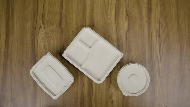 Stop motion video of placing packaged food boxes on table - concept of biodegradable or eco friendly plastic free food packing.