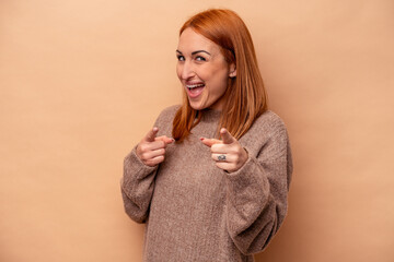 Young caucasian woman isolated on beige background pointing to front with fingers.