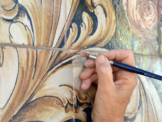 Restorer reintegrating the color of an old tile with a brush. Restoration and conservation of old...