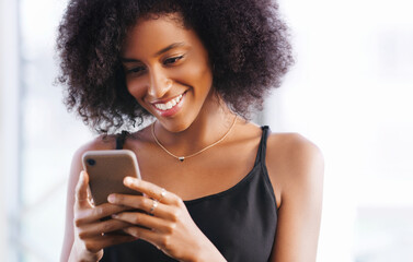 Some messages are instant happiness boosters. Shot of a happy young woman using a smartphone.