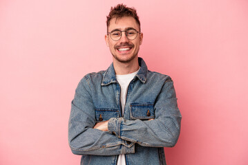Young caucasian man isolated on pink background who feels confident, crossing arms with determination.