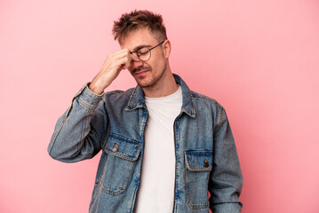 Young caucasian man isolated on pink background having a head ache, touching front of the face.