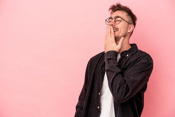 Young caucasian man isolated on pink background laughing happy, carefree, natural emotion.