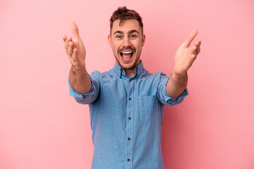 Fototapeta premium Young caucasian man isolated on pink background feels confident giving a hug to the camera.