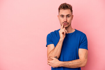 Young caucasian man isolated on pink background looking sideways with doubtful and skeptical expression.