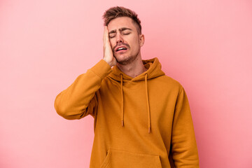 Young caucasian man isolated on pink background tired and very sleepy keeping hand on head.