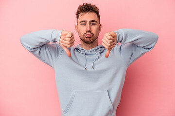 Young caucasian man isolated on pink background showing a dislike gesture, thumbs down. Disagreement concept.