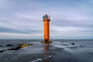 An orange lighthouse at the end of the Mangalsala or Eastern pier in Riga, Latvia where the river...