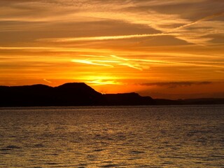 Naklejka na ściany i meble vivid orange sunrise over the sea and cliffs