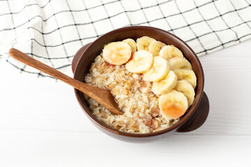 Healthy breakfast. oatmeal with bananas on a white table