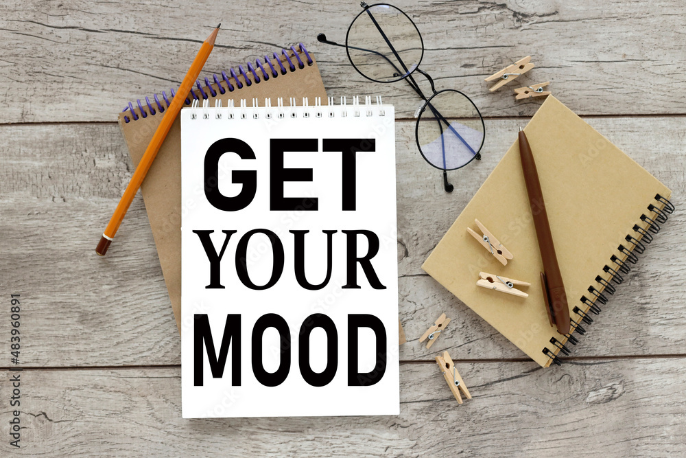 Poster GET YOUR MOOD text on open notepad on wooden background different stationery and glasses