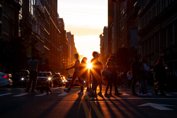 Silhouettes of men and women crossing a busy street in Midtown Manhattan, New York City with...
