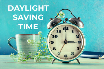 Daylight Saving Time concept, spring forward. A retro alarm clock with a coffee cup and fresh...
