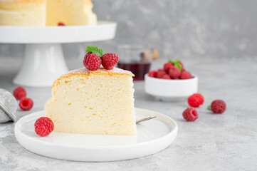 Japanese cotton cheesecake on a stand on a gray concrete background with fresh raspberries and powdered sugar on top. Selective focus, copy space. - obrazy, fototapety, plakaty