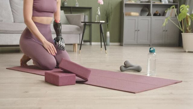 Slowmo shot of young fit woman with bionic arm standing in plank position whilst training at home