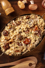 Risotto ai funghi, rustic mushroom rice, with ingredients, shot from above on a dark wooden background