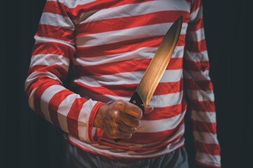 Man wearing joker mask with knife.