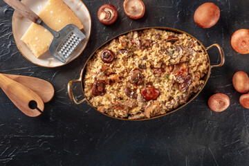 Risotto ai funghi, mushroom rice with cheese, with ingredients, overhead flat lay shot on a black slate background with a place for text